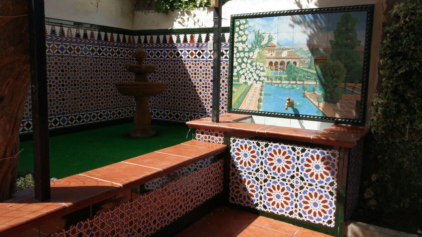 Patio andaluz con banco y fuente revestidos de azulejo artesano